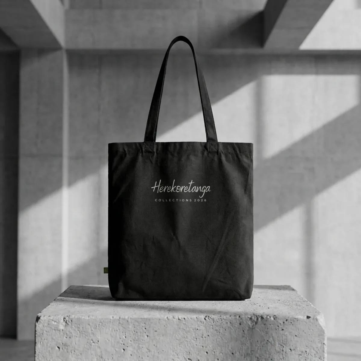 Equipment Herekoretanga: borsa Archive Tote in canvas nero 407g/m² su blocco di cemento. Equipaggiamento industriale ispirato alle rotte di Oceania e al rigore della cultura Maori. Design GL MANIFACTORY.
