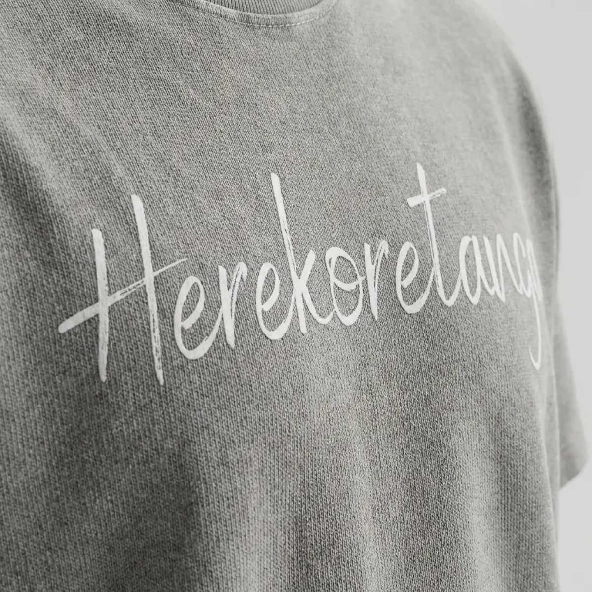 Dettaglio macro modulo Grigio Asfalto Herekoretanga: jersey pesante con lavaggio acido minerale e stampa grafica. Texture ispirata all'erosione naturale di Oceania e alla forza della terra Maori. Standard GL MANIFACTORY.
