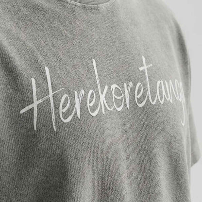 Dettaglio macro modulo Grigio Asfalto Herekoretanga: jersey pesante con lavaggio acido minerale e stampa grafica. Texture ispirata all'erosione naturale di Oceania e alla forza della terra Maori. Standard GL MANIFACTORY.
