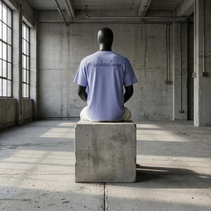 Modulo Herekoretanga: maglia azzurra 240g su manichino seduto in ambiente industriale di cemento. Estetica del rigore ispirata alla solitudine di Oceania e alla forza Maori. Design GL MANIFACTORY.

