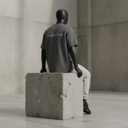 Modulo Herekoretanga: maglia color erica carbone 240g su manichino in ambiente industriale brutalista. Estetica del rigore ispirata alle pietre laviche di Oceania e alla forza della cultura Maori. Design GL MANIFACTORY.
