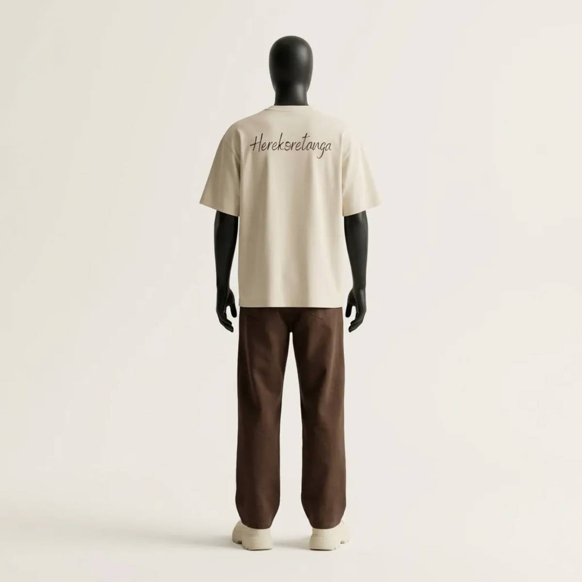 Modulo Herekoretanga: prospettiva posteriore maglia color sabbia 240g/m² su manichino tecnico nero. Studio del volume boxy con grafica "Herekoretanga" ispirato al rigore di Oceania e alla forza della cultura Maori. Architettura tessile GL MANIFACTORY.