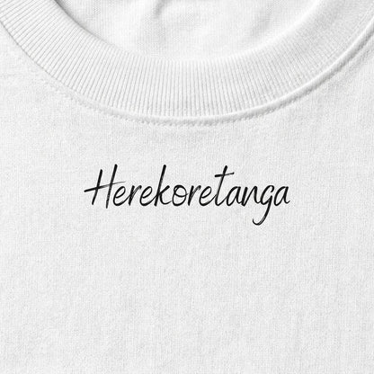 Dettaglio macro della stampa calligrafica "Herekoretanga" su cotone bianco. Il close-up esalta la trama del tessuto heavy-duty e la precisione del contrasto cromatico, pilastri del design GL MANIFACTORY